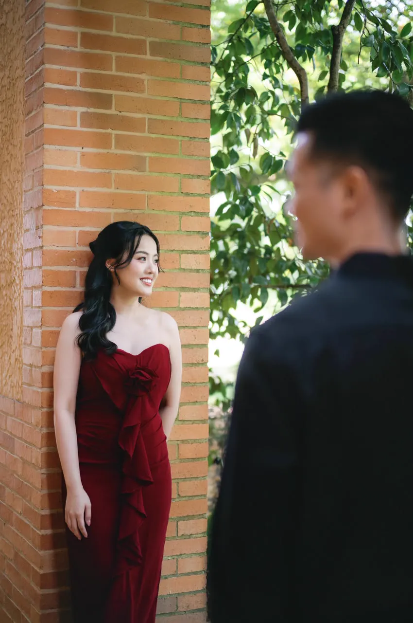 Vivi leaning on a brick wall, smiling at Max