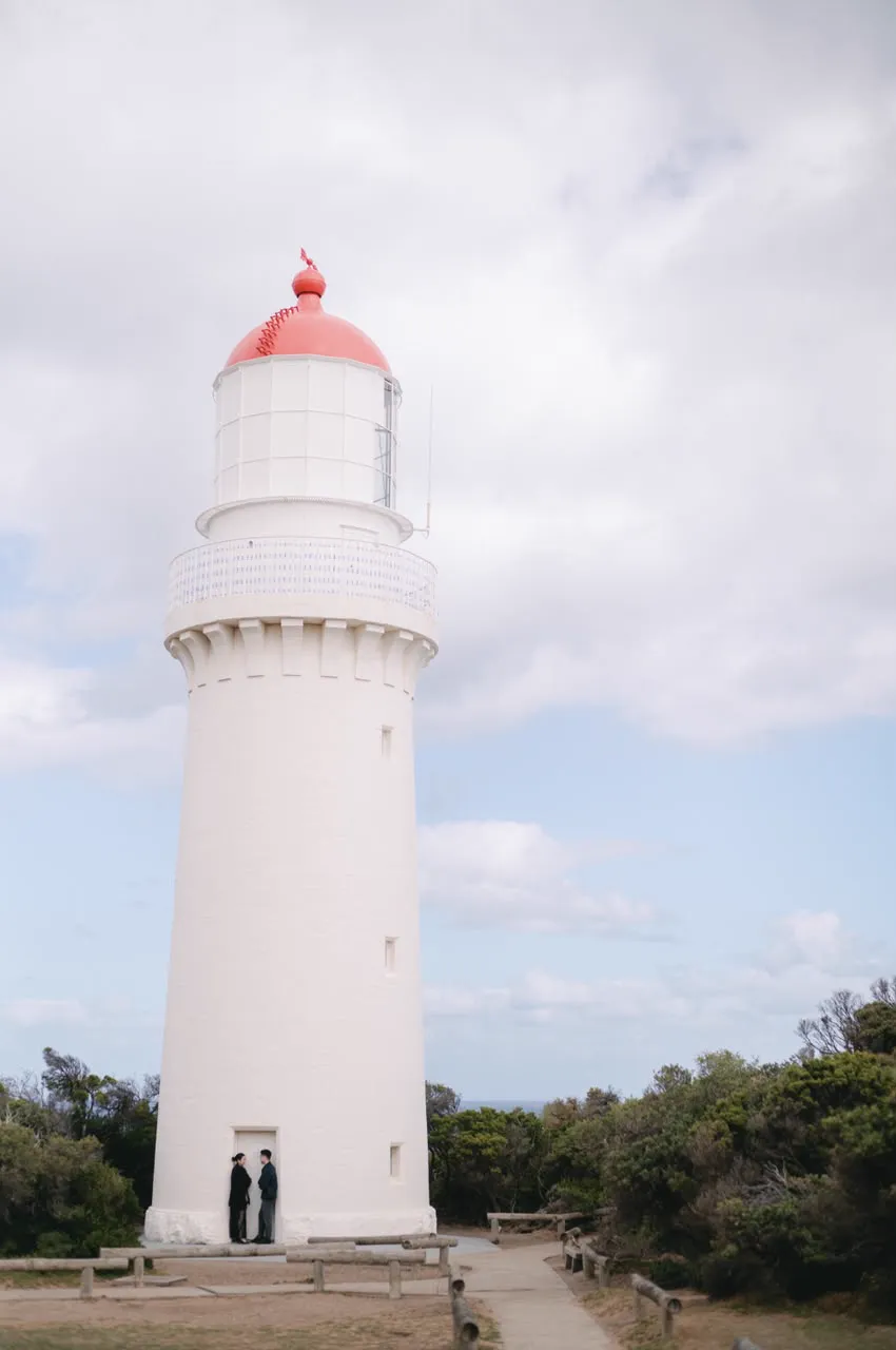 Vivi and Max at the foot of a tall white lighthouse